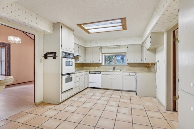 kitchen featuring white cabinetry, tasteful backsplash, white appliances, sink, and light tile patterned floors