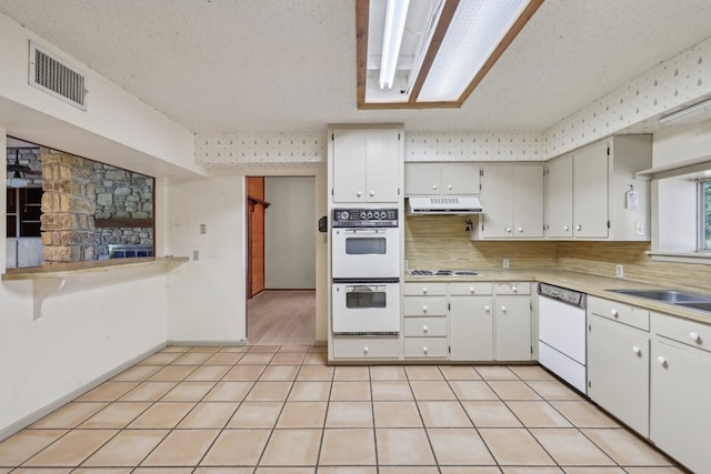 kitchen featuring tasteful backsplash, white appliances, sink, a textured ceiling, and light tile patterned floors