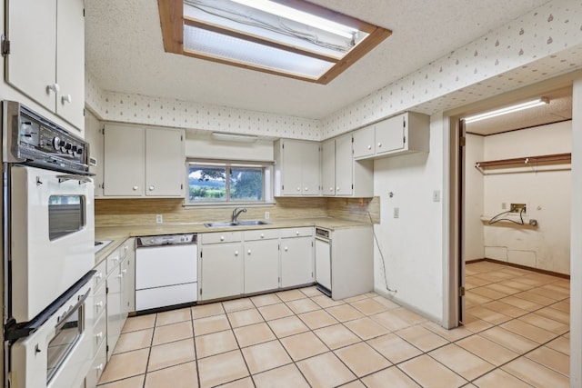 kitchen featuring white cabinets, white appliances, sink, light tile patterned floors, and decorative backsplash