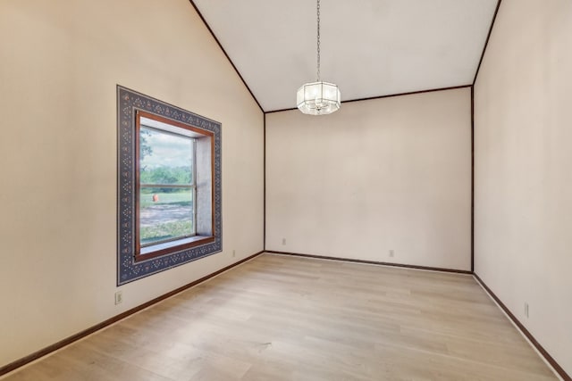 spare room with lofted ceiling, light hardwood / wood-style floors, and a notable chandelier