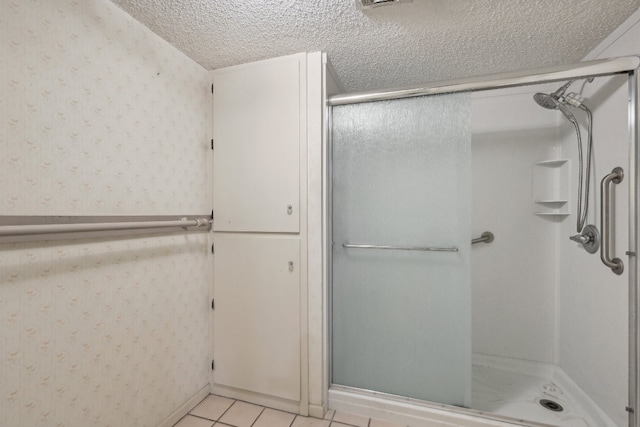 bathroom with tile patterned floors, a textured ceiling, and an enclosed shower