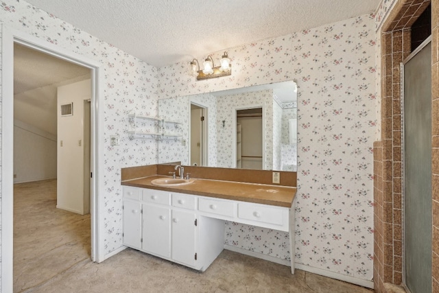 bathroom featuring a shower with door, vanity, and a textured ceiling