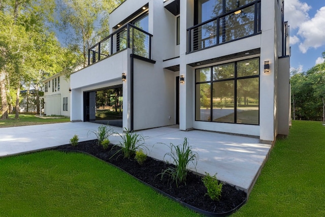 entrance to property featuring a yard and a balcony