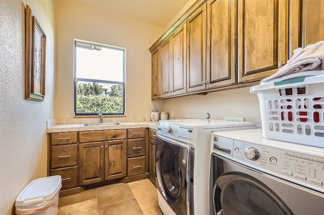 laundry area with light tile patterned floors, independent washer and dryer, cabinets, and sink