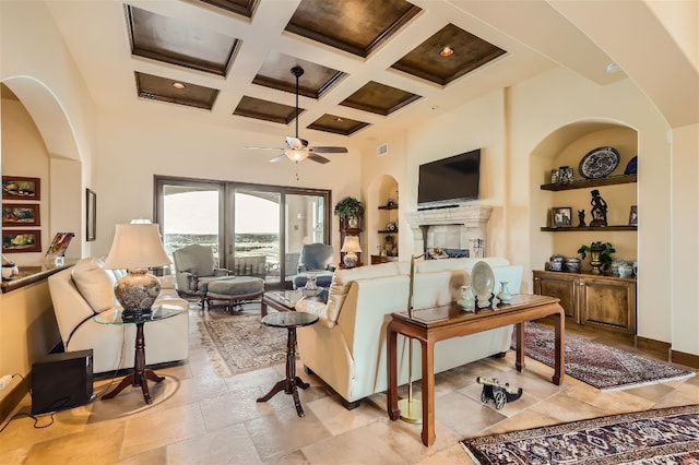 living room with ceiling fan, coffered ceiling, beam ceiling, and a high ceiling