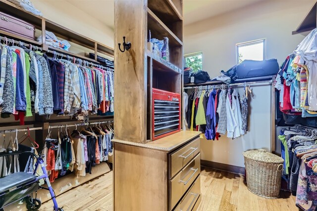 walk in closet with light hardwood / wood-style floors