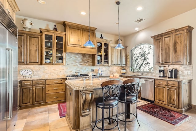 kitchen with light stone countertops, light tile patterned floors, decorative backsplash, and a center island with sink