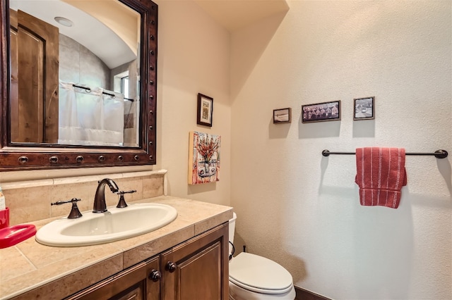 bathroom with a shower with shower curtain, vanity, toilet, and decorative backsplash