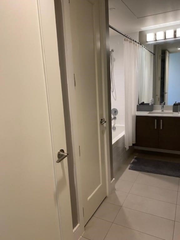 bathroom featuring tile patterned flooring, vanity, and shower / bath combo with shower curtain