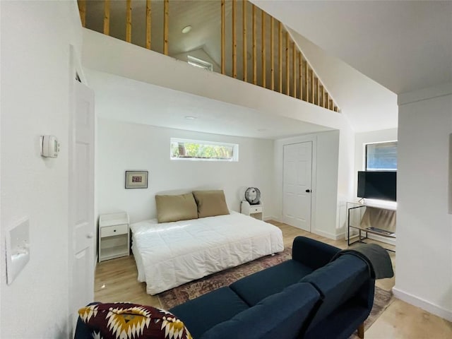 bedroom with high vaulted ceiling and light hardwood / wood-style flooring