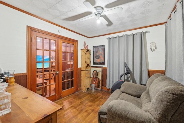 living room with french doors, ornamental molding, ceiling fan, hardwood / wood-style floors, and wood walls