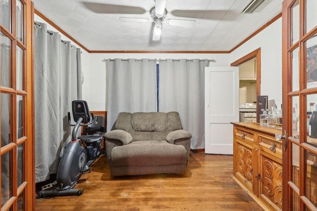 living area with ceiling fan, crown molding, and light hardwood / wood-style flooring