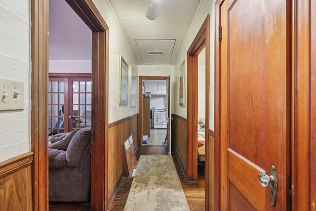 hallway with ornamental molding, wooden walls, and french doors