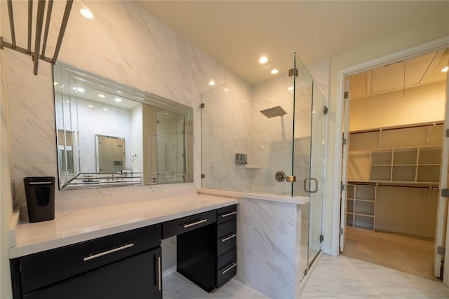 bathroom with vanity, a shower with door, and tile walls