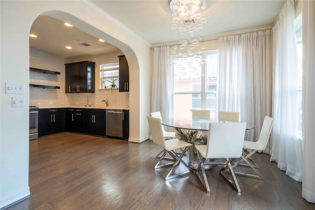 dining room featuring a notable chandelier, dark hardwood / wood-style flooring, sink, and crown molding