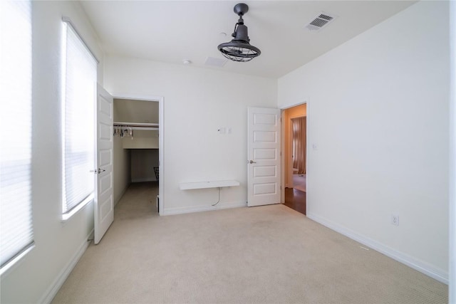 unfurnished bedroom with light colored carpet, multiple windows, and a closet