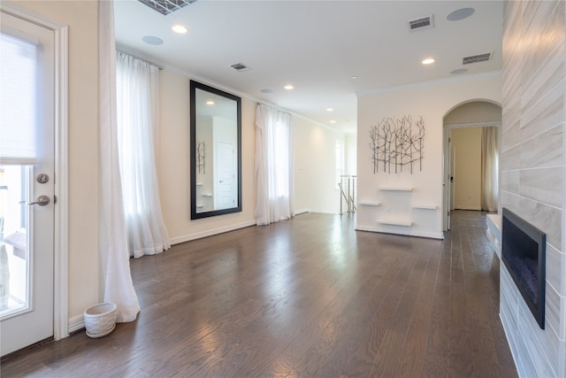 unfurnished living room featuring dark wood-type flooring and ornamental molding