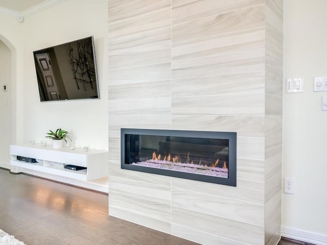 interior details with a fireplace, wood-type flooring, and ornamental molding