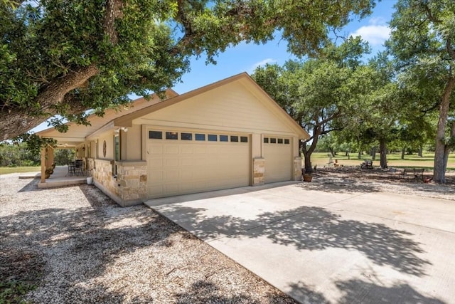 view of home's exterior with a garage, stone siding, concrete driveway, and an outbuilding