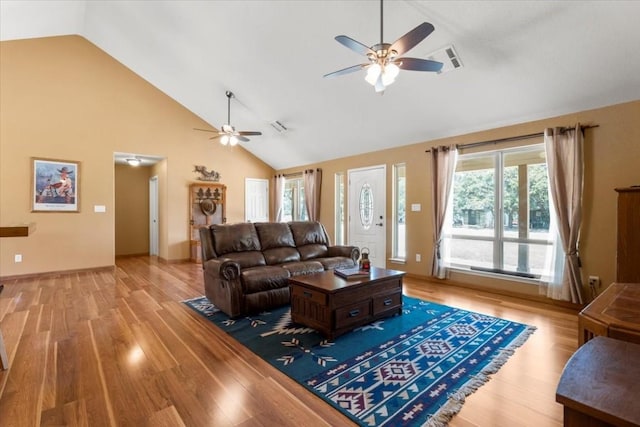 living room with light wood-style floors, visible vents, ceiling fan, and high vaulted ceiling