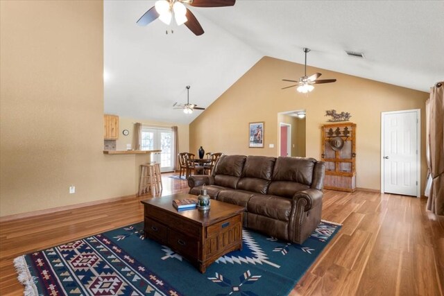 living room with hardwood / wood-style floors, high vaulted ceiling, and ceiling fan