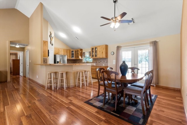 dining space with light hardwood / wood-style floors, french doors, ceiling fan, and high vaulted ceiling