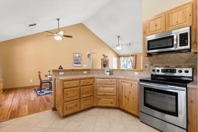 kitchen featuring ceiling fan, stainless steel appliances, high vaulted ceiling, light wood-type flooring, and kitchen peninsula