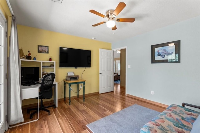 home office with a ceiling fan, baseboards, and wood finished floors