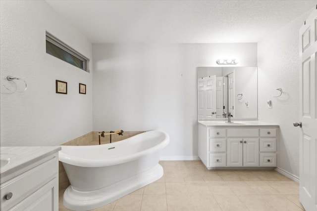 bathroom with dual vanity, a textured ceiling, a bathtub, and tile patterned floors