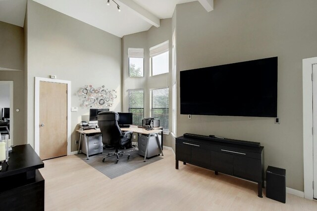 office with beamed ceiling, light hardwood / wood-style flooring, a towering ceiling, and track lighting