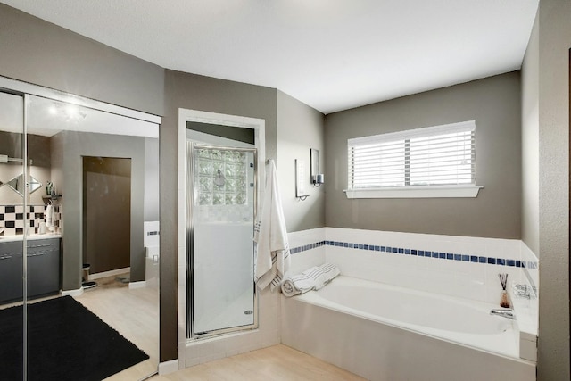 bathroom with plus walk in shower, hardwood / wood-style floors, and vanity