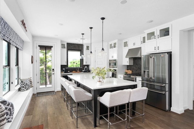 kitchen with a kitchen bar, white cabinetry, tasteful backsplash, a center island, and appliances with stainless steel finishes