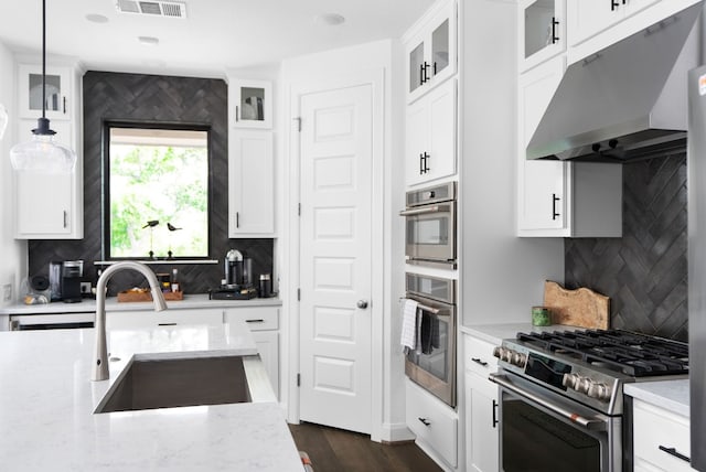 kitchen with appliances with stainless steel finishes, sink, pendant lighting, and white cabinets