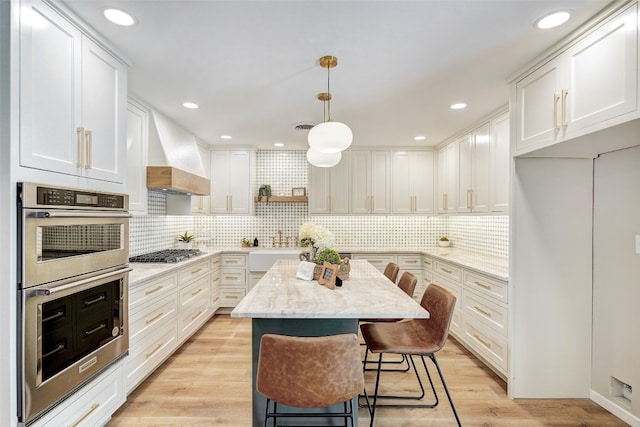 kitchen with appliances with stainless steel finishes, white cabinetry, and pendant lighting