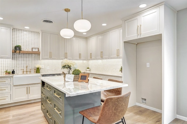 kitchen featuring white cabinets, sink, a kitchen island, and hanging light fixtures