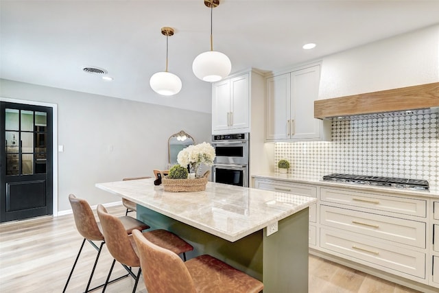 kitchen with a center island, white cabinets, light hardwood / wood-style flooring, and appliances with stainless steel finishes