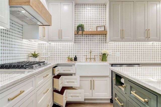 kitchen featuring green cabinets, decorative backsplash, custom range hood, and stainless steel gas cooktop