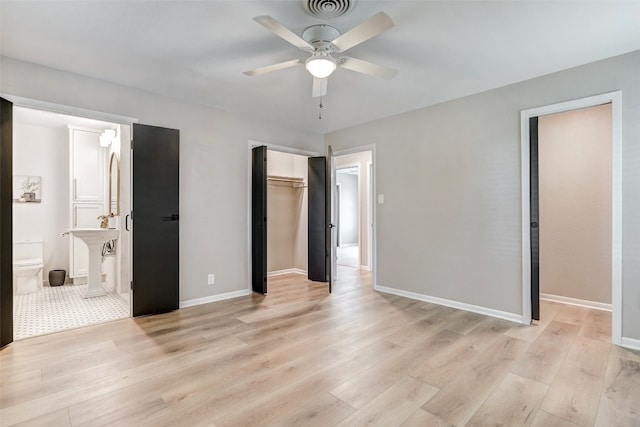 unfurnished bedroom with ensuite bathroom, a closet, ceiling fan, and light wood-type flooring