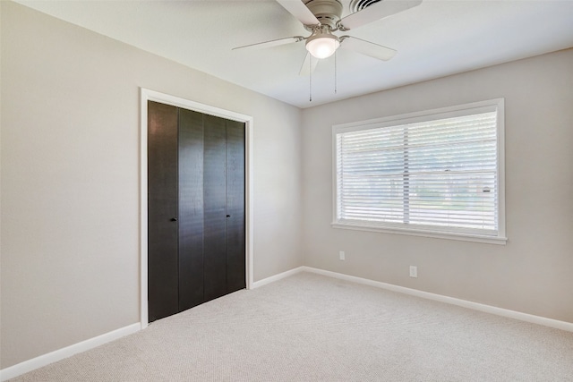 unfurnished bedroom with carpet, a closet, and ceiling fan