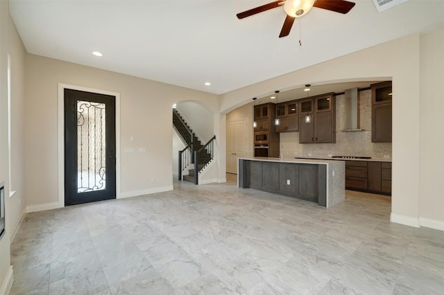 interior space with light tile patterned flooring, dark brown cabinets, decorative backsplash, and wall chimney exhaust hood