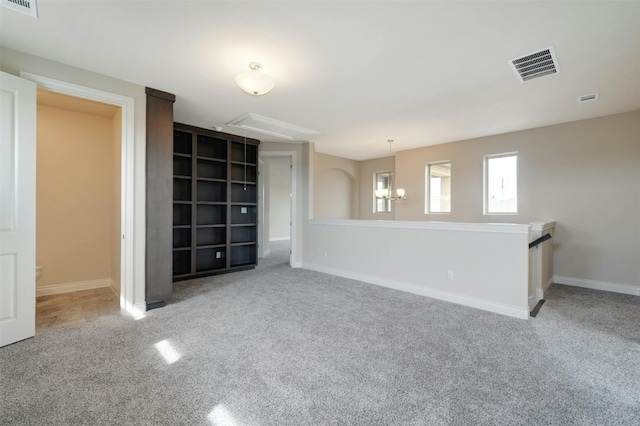 empty room featuring carpet flooring and a notable chandelier