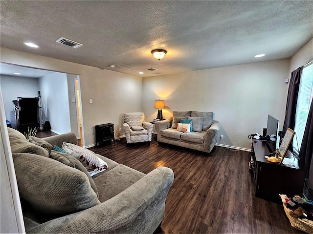 living area with dark wood finished floors, visible vents, a textured ceiling, and baseboards