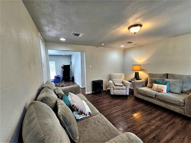 living room with baseboards, wood finished floors, visible vents, and a textured ceiling