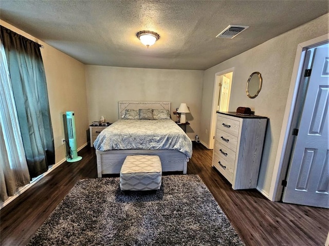 bedroom featuring visible vents, baseboards, dark wood-type flooring, and a textured ceiling