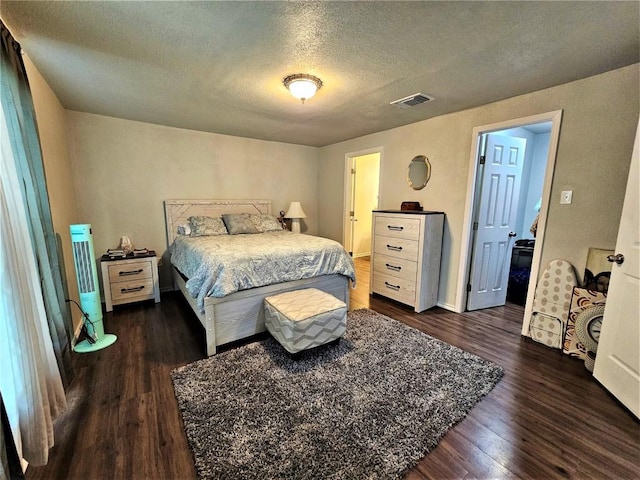 bedroom featuring dark wood finished floors, visible vents, and a textured ceiling