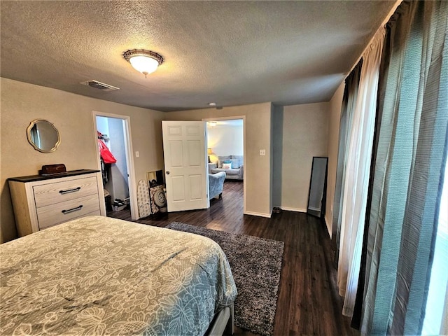 bedroom with visible vents, a textured ceiling, dark wood-type flooring, and baseboards