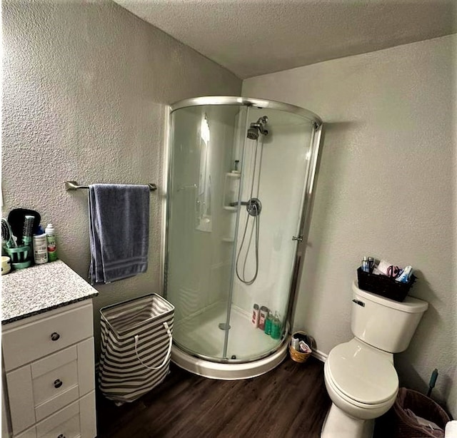 bathroom featuring a textured ceiling, wood finished floors, a shower stall, and a textured wall