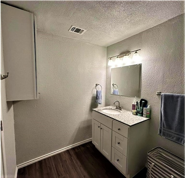 bathroom with wood-type flooring, vanity, and a textured ceiling