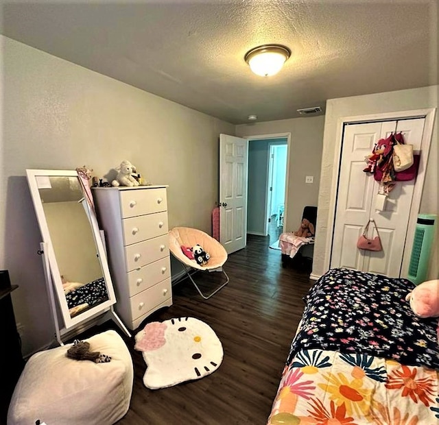 bedroom with visible vents, dark wood-type flooring, baseboards, a closet, and a textured ceiling