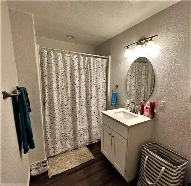 bathroom featuring a shower with shower curtain, vanity, a textured wall, wood finished floors, and a textured ceiling